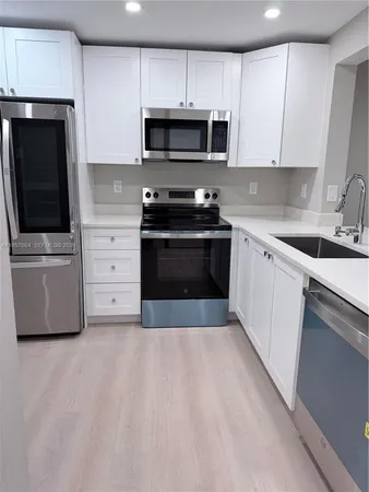 a kitchen with stainless steel appliances a stove a microwave a sink and cabinets