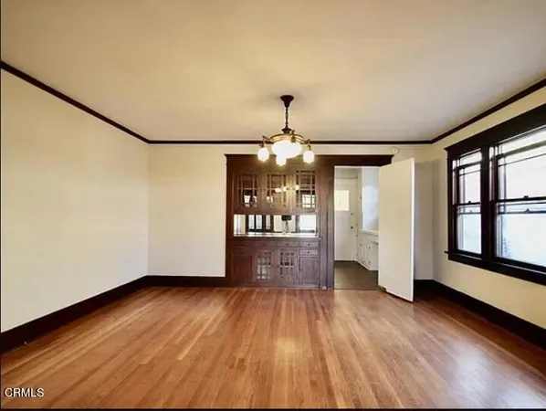 a view of an empty room with wooden floor fireplace and a window