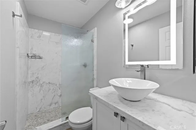 a bathroom with a granite countertop sink toilet a mirror and shower