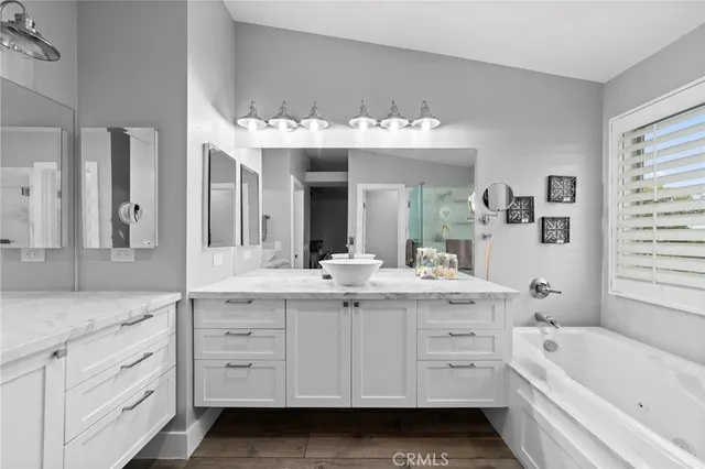 a bathroom with a sink vanity granite tub shower and a mirror