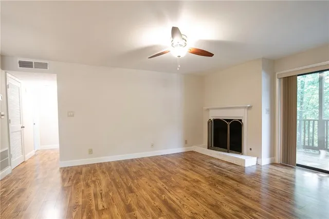 an empty room with wooden floor fireplace and windows