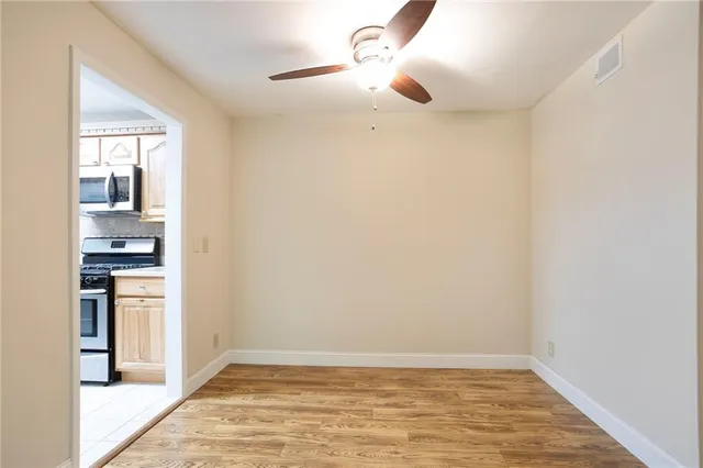 a view of kitchen and empty room with wooden floor