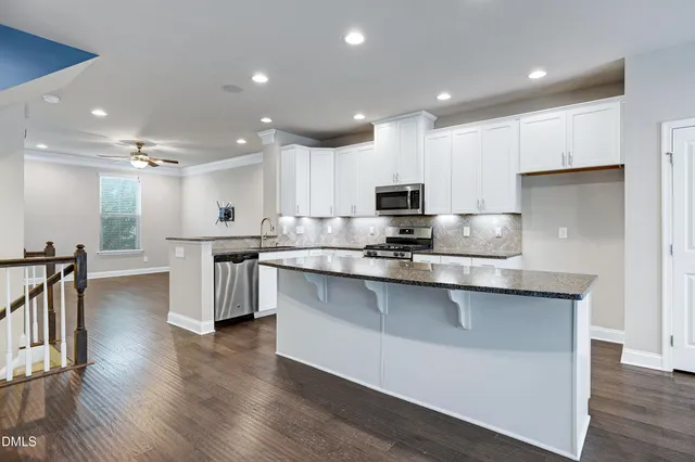 a kitchen with stainless steel appliances kitchen island granite countertop a table chairs and a refrigerator