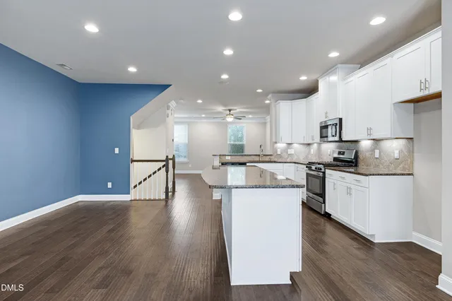 an empty room with wooden floor ceiling fan and windows