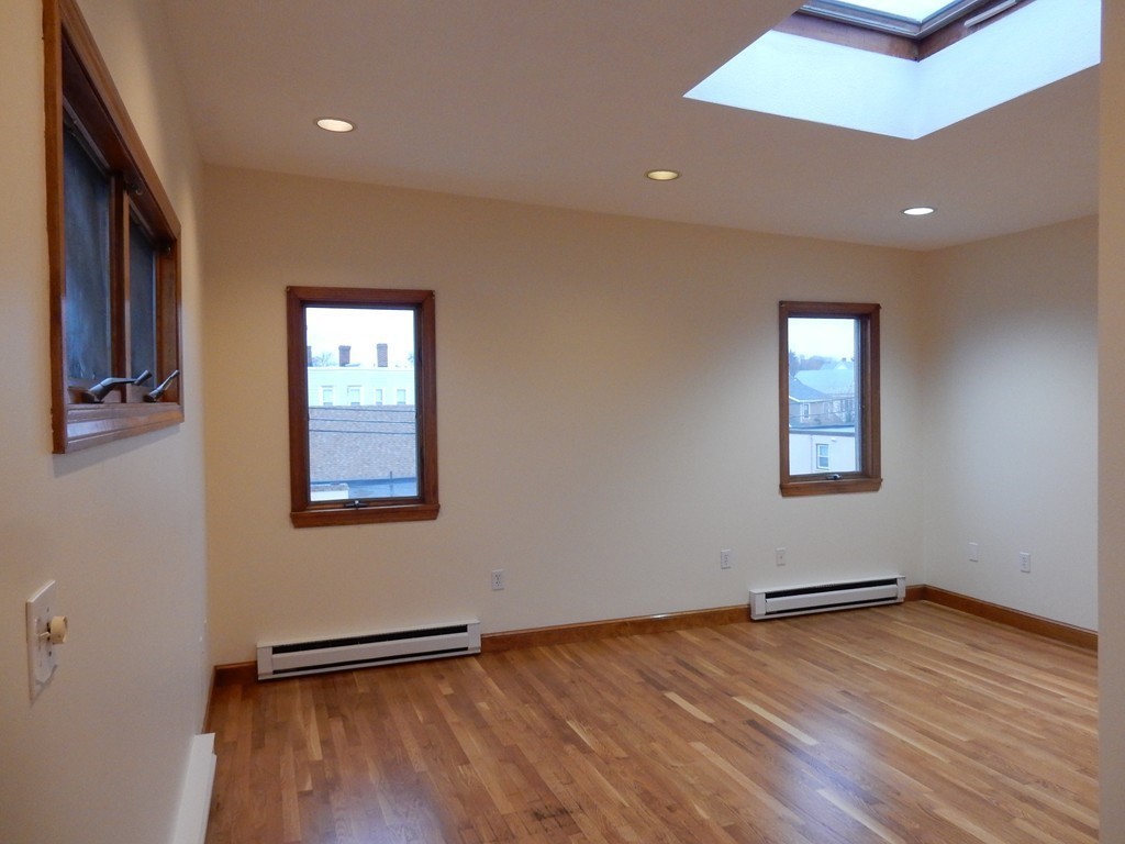 63 Bucknam Street Everett, MA 02149 - Photo 21 of 28 an empty room with wooden floor and windows