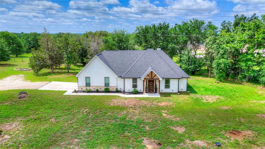 1355 Jay Bird Road Springtown, TX 76082 - Photo 3 of 40 a house that is sitting in the grass with large trees and plants
