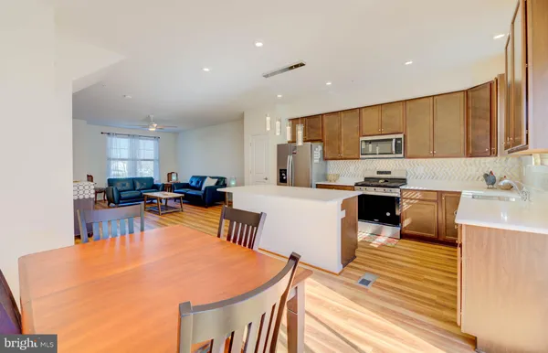 a kitchen with stainless steel appliances a stove a sink a refrigerator white cabinets and wooden floor