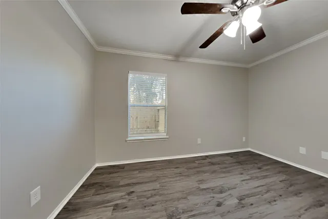 an empty room with wooden floor ceiling fan and window