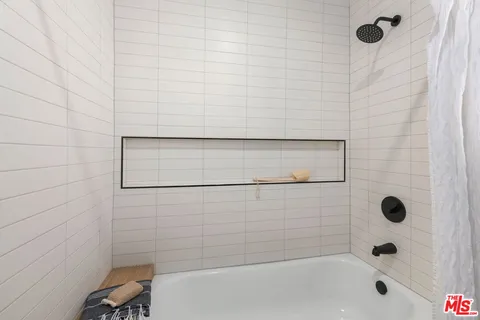 a view of a hallway with wooden floor and a bathroom