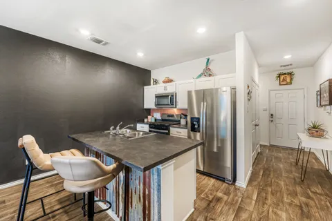 a kitchen with stainless steel appliances granite countertop a table chairs and a refrigerator