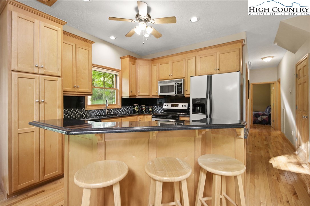 105 Old Field Road Beech Mountain, NC 28604 - Photo 21 of 43 a kitchen with stainless steel appliances granite countertop a stove a refrigerator a sink a dining table and chairs with wooden floor