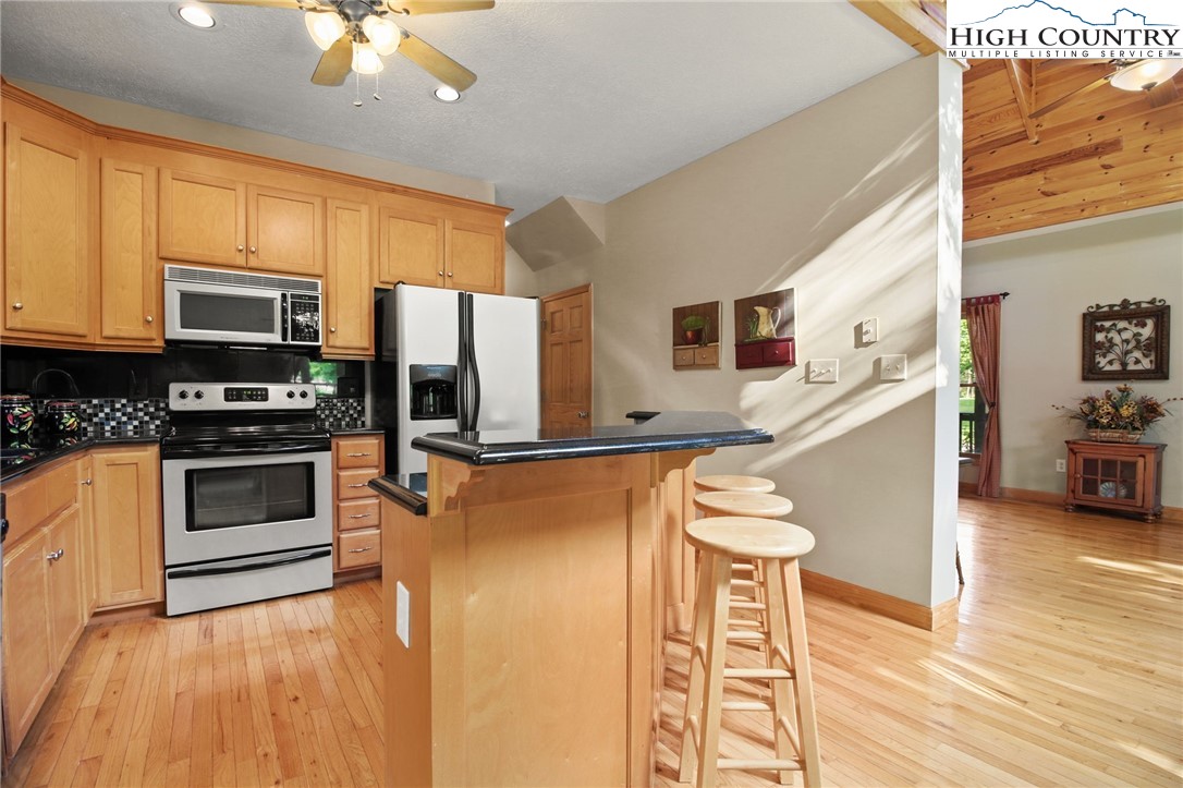 105 Old Field Road Beech Mountain, NC 28604 - Photo 22 of 43 a kitchen with stainless steel appliances a stove top oven a sink dishwasher and a refrigerator with wooden floor