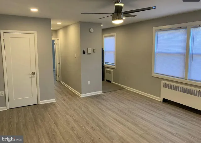 an empty room with wooden floor cabinet and windows