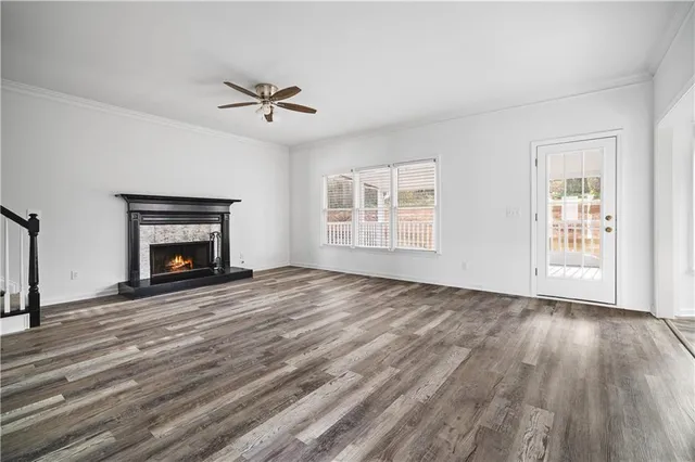 a view of an empty room with wooden floor fireplace and a window