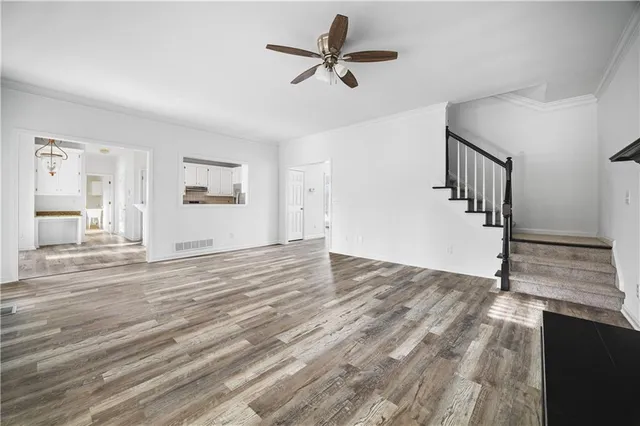 a view of an empty room with wooden floor and a ceiling fan