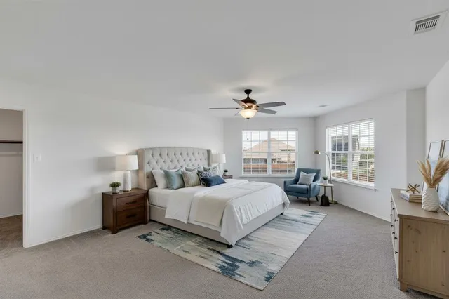 a spacious bedroom with a bed couch and windows