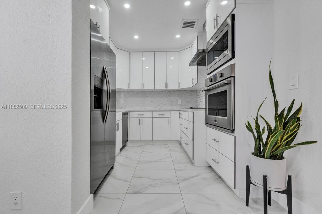 6470 Southwest 27th Street Miami, FL 33155 - Photo 9 of 38 a kitchen with white cabinets and stainless steel appliances