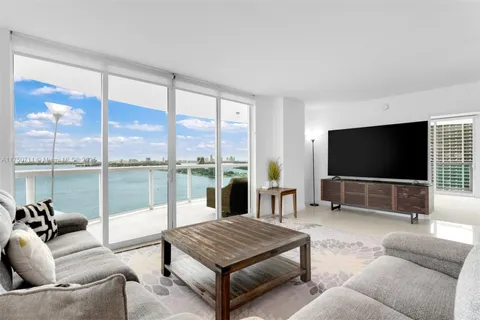 a living room with furniture floor to ceiling window and a flat screen tv