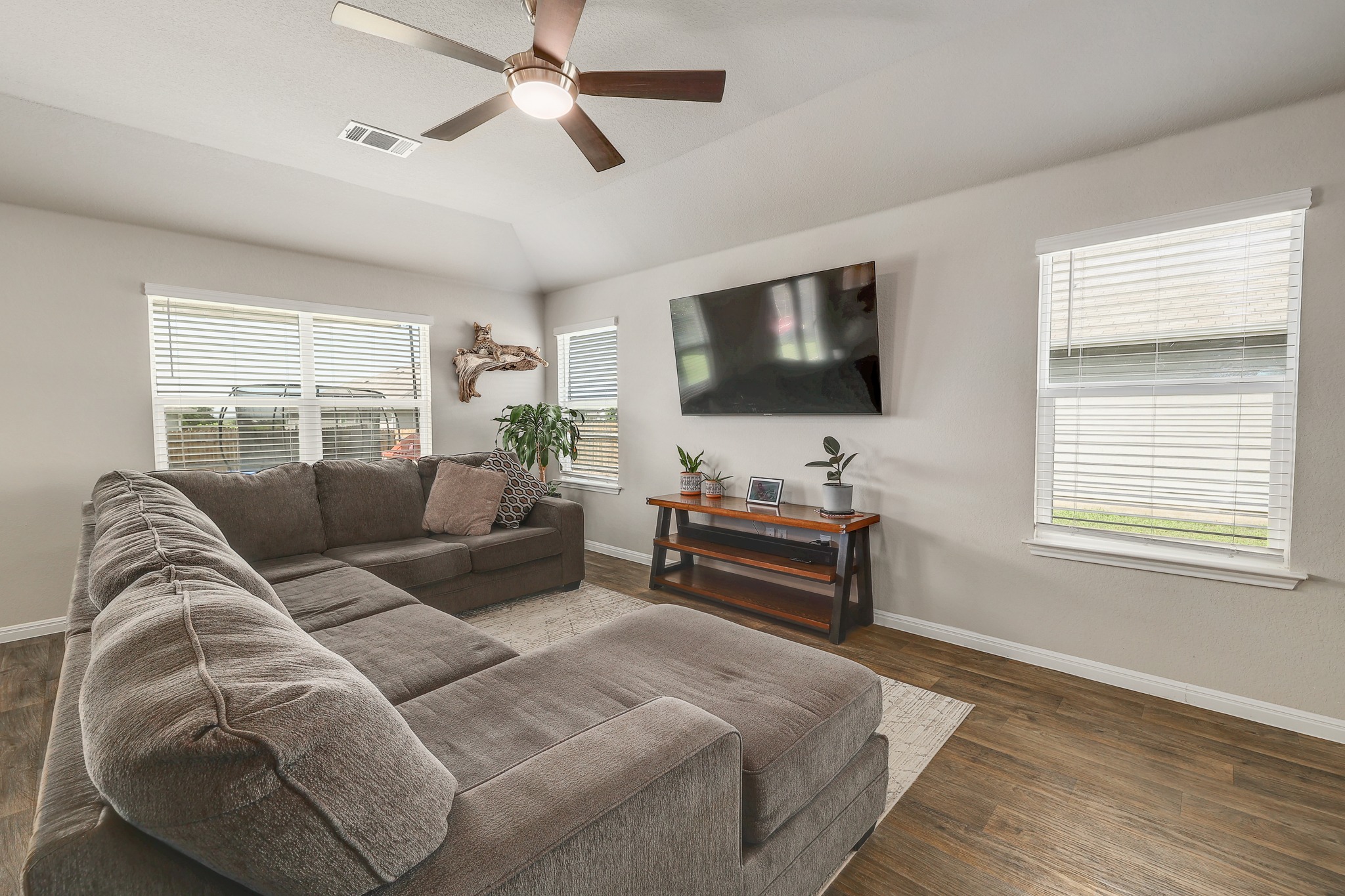 413 Hunter Loop Bertram, TX 78605 - Photo 5 of 27 The living room offers a comfortable gathering space with vinyl plank flooring, large windows and a high ceiling.