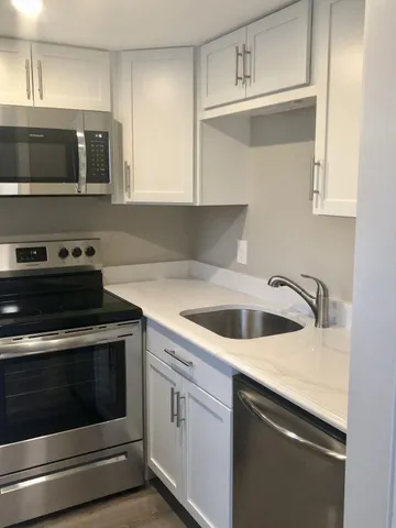 a kitchen with granite countertop a stove top oven microwave and cabinets
