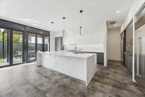 a large white kitchen with stainless steel appliances large windows
