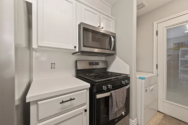 a kitchen with stainless steel appliances granite countertop white cabinets and black stove top oven