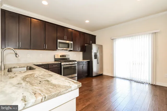 a kitchen with stainless steel appliances granite countertop a refrigerator stove top oven and sink