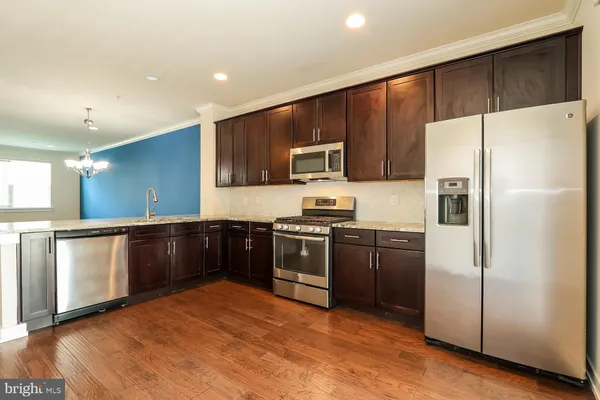 a kitchen with stainless steel appliances kitchen island granite countertop a refrigerator a sink a stove a microwave and island with wooden floor