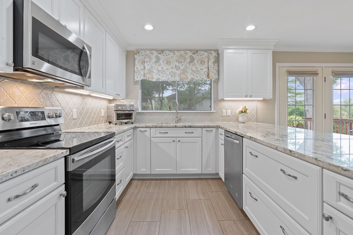 a kitchen with granite countertop cabinets stainless steel appliances a sink and window