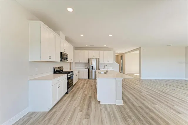a large white kitchen with wooden floors and stainless steel appliances