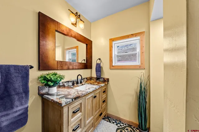 a bathroom with a granite countertop sink and a mirror