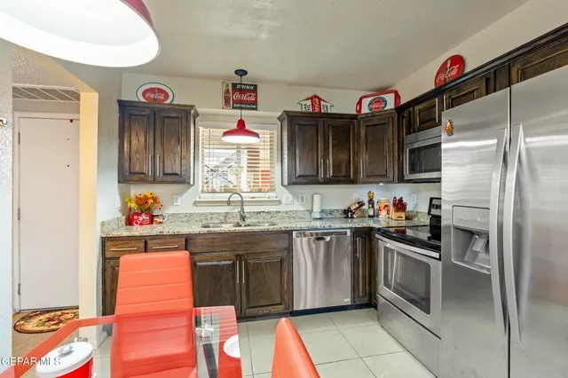 a kitchen with granite countertop stainless steel appliances a sink and a refrigerator