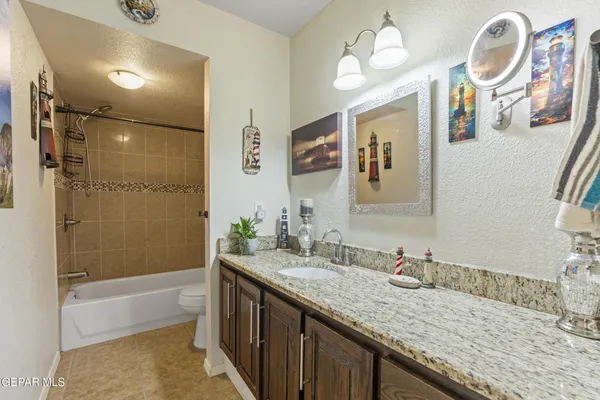 a bathroom with a granite countertop sink mirror and a bath tub