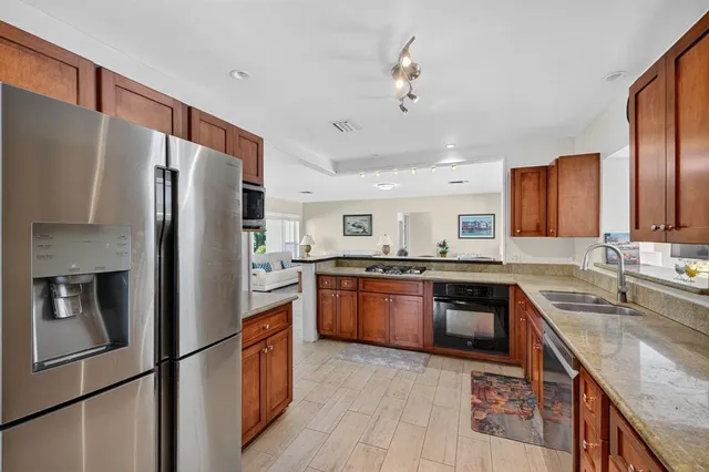 a kitchen with stainless steel appliances granite countertop a refrigerator a stove top oven and sink