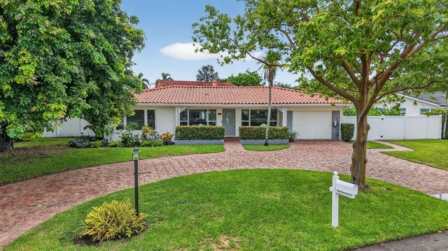 a view of house with a big yard potted plants and large tree