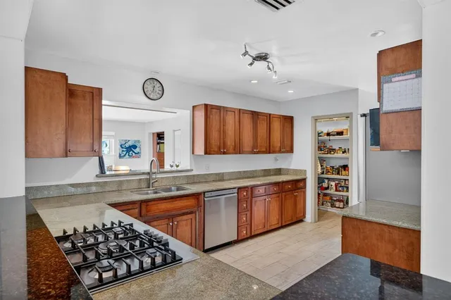 a kitchen with stainless steel appliances granite countertop wooden cabinets stove top oven and sink