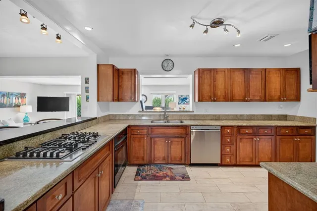 a kitchen with stainless steel appliances granite countertop a refrigerator a stove top oven a sink and dishwasher