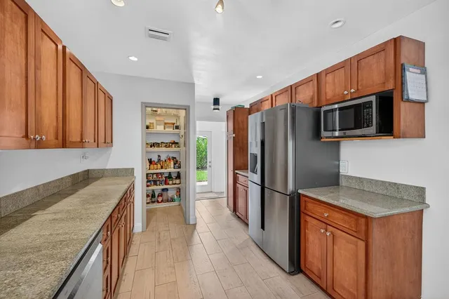 a kitchen with stainless steel appliances granite countertop a refrigerator a stove a sink and a refrigerator