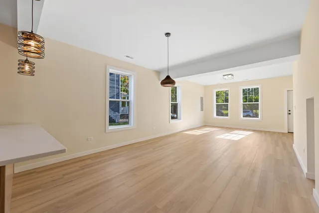 a view of an empty room with window and wooden floor