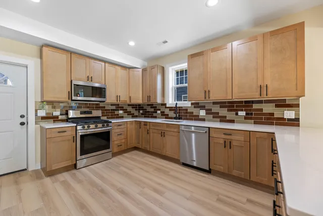 a kitchen with stainless steel appliances granite countertop a stove a sink and a microwave