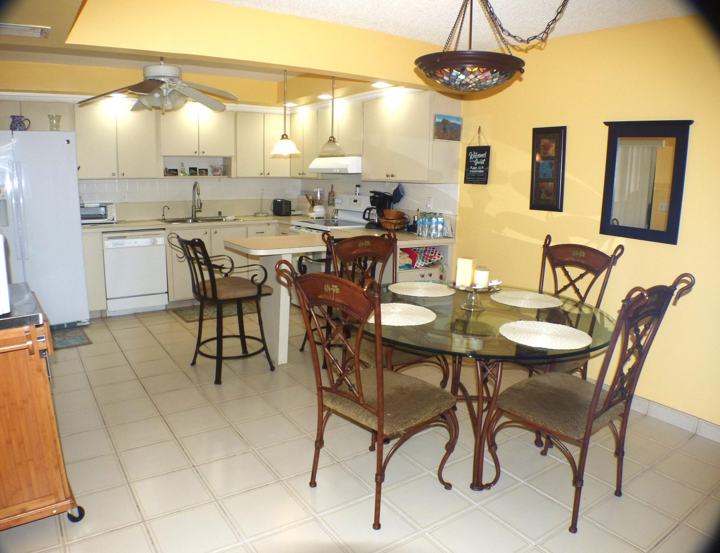 2686 Northwest 7th Court, Unit C Delray Beach, FL 33445 - Photo 5 of 33 a dining room with stainless steel appliances kitchen island granite countertop a table chairs and a refrigerator