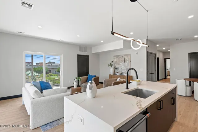 a kitchen with stainless steel appliances a stove top oven a sink a refrigerator with wooden floor and cabinets