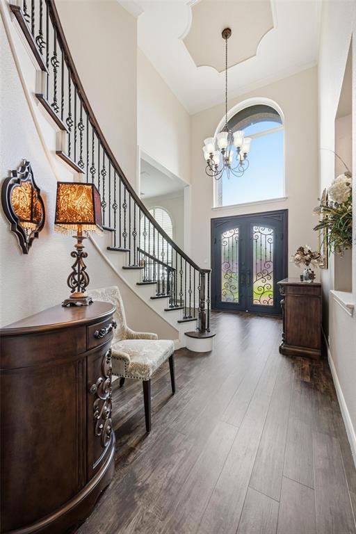 9305 Anns Way Plano, TX 75025 - Photo 12 of 39 Entryway with dark wood-style flooring, stairway, a chandelier, a high ceiling, and crown molding