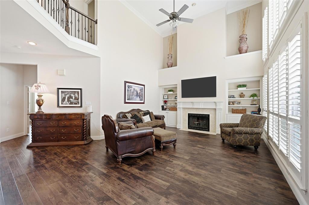 9305 Anns Way Plano, TX 75025 - Photo 4 of 39 Living room with a towering ceiling, a fireplace with flush hearth, dark wood-style floors, crown molding, and ceiling fan