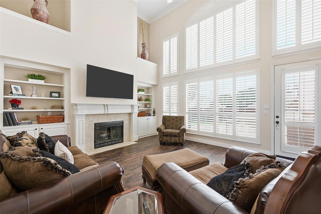 9305 Anns Way Plano, TX 75025 - Photo 6 of 39 Living room featuring a high ceiling, a fireplace with flush hearth, crown molding, dark wood finished floors, and built in features