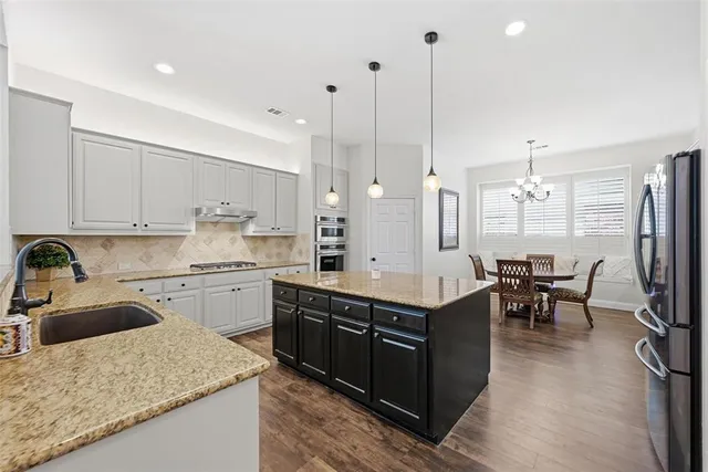 a kitchen with stainless steel appliances granite countertop sink stove top oven and cabinets