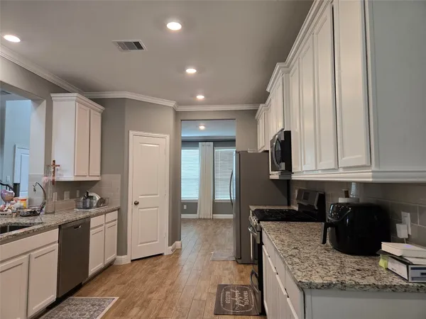 a kitchen with granite countertop a refrigerator a sink and white cabinets