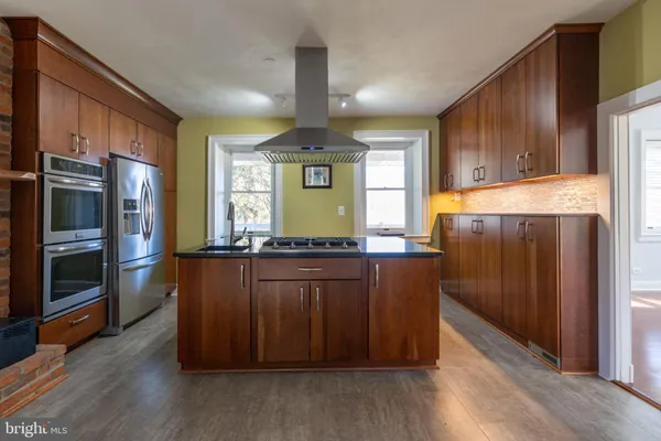a view of an empty room with wooden floor fireplace and a window
