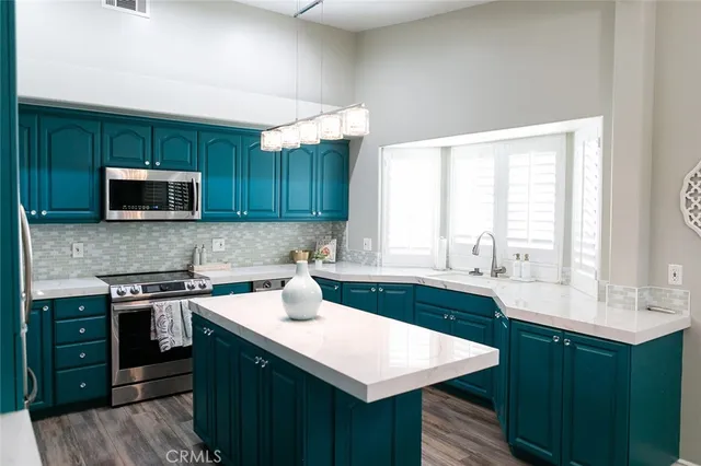 a kitchen with stainless steel appliances a sink a stove a refrigerator cabinets and wooden floor