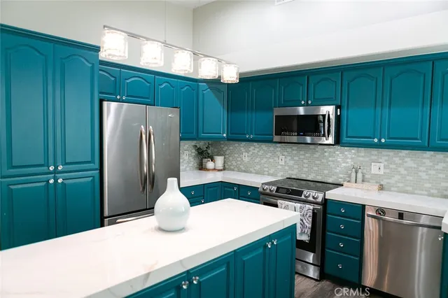 a kitchen with stainless steel appliances a sink a stove a microwave cabinets and a window